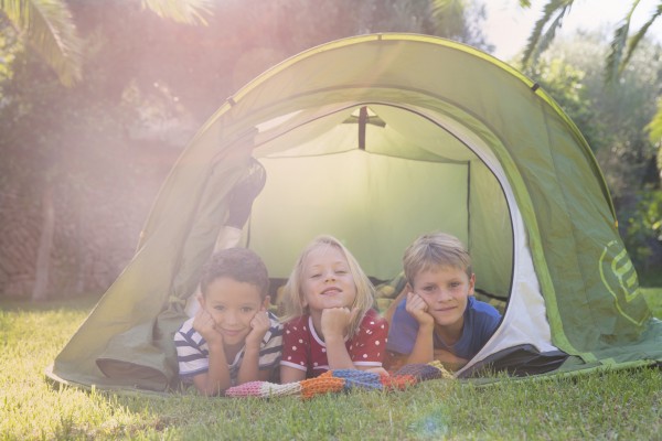 Portrait of three children lying in garden tent